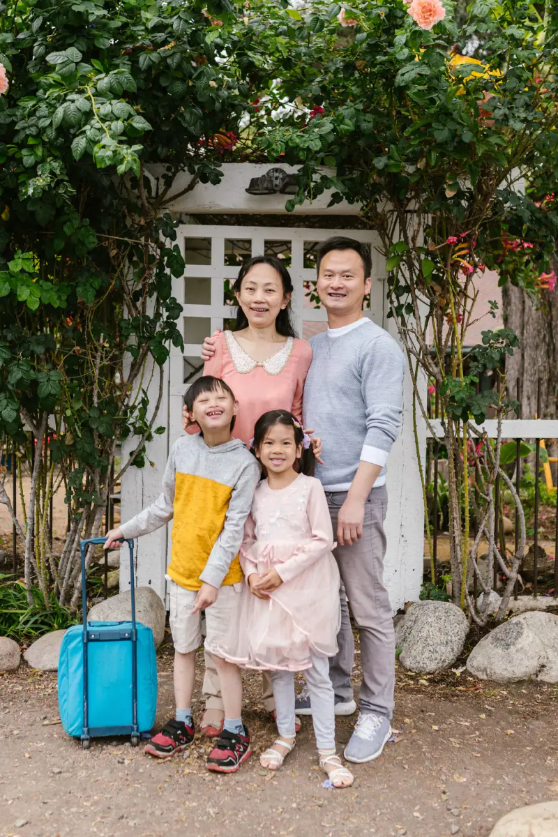 A family smiling together outdoors, including a young person with Down syndrome.
