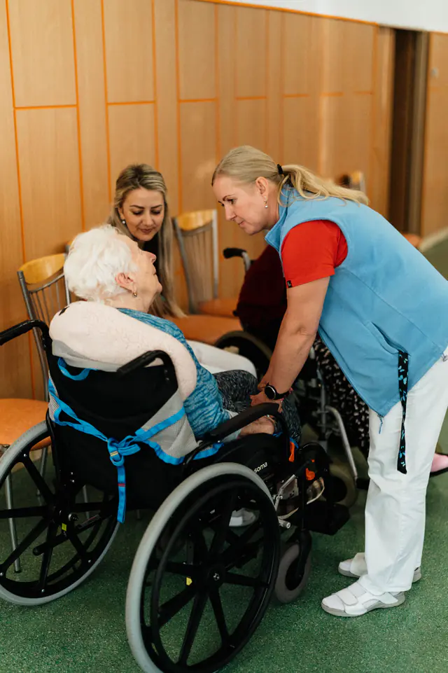 A caregiver talking with an older woman using a wheelchair.